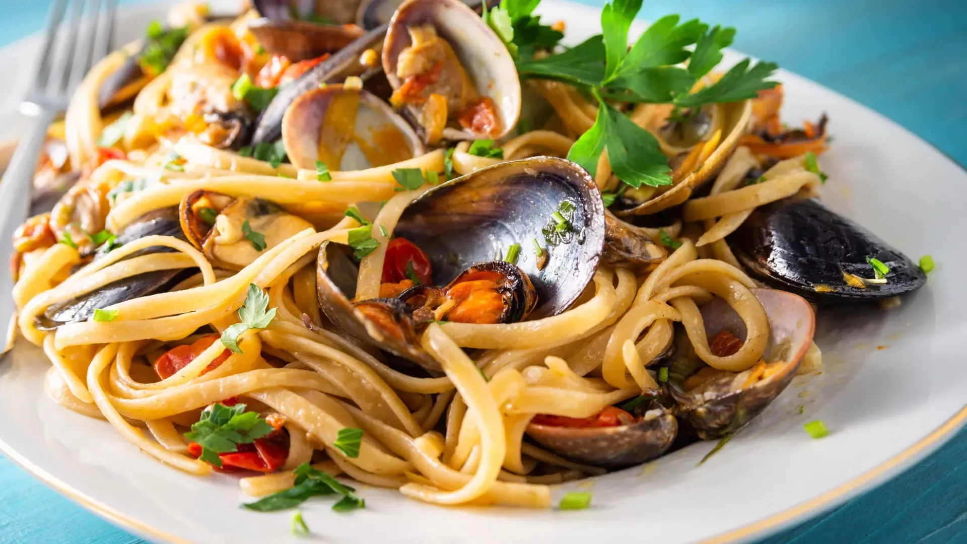 Piatto di linguine ai frutti di mare con vongole, cozze e prezzemolo fresco.