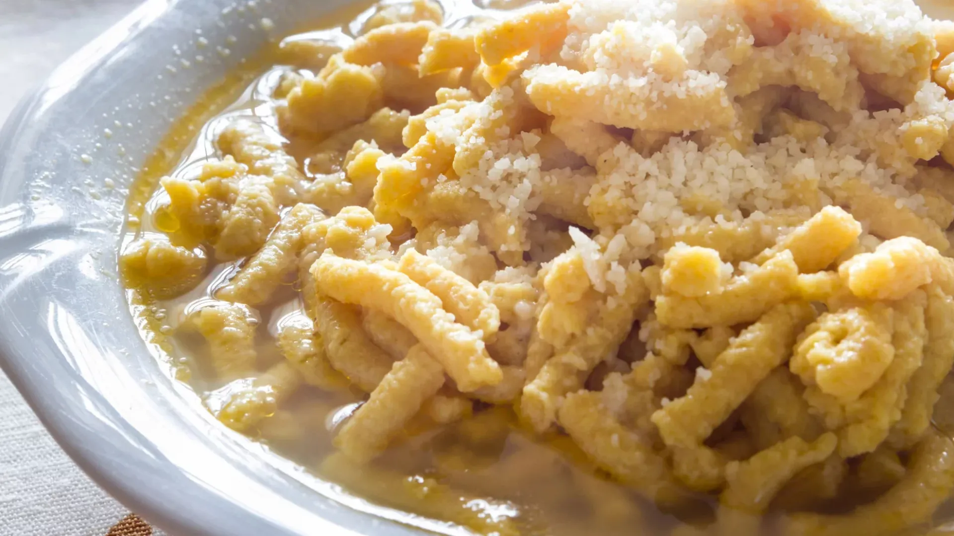 Passatelli in brodo, un piatto tradizionale italiano con formaggio grattugiato.