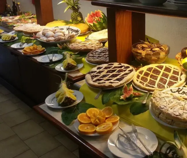 Buffet con torte, frutta fresca e dolci vari su un tavolo decorato.