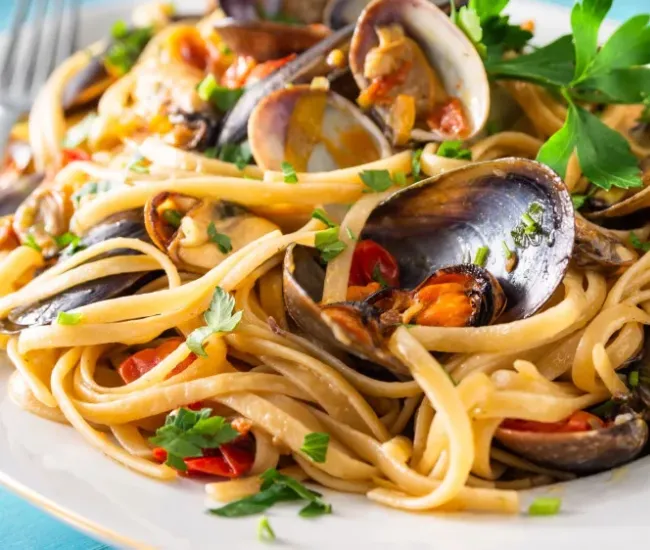 Linguine con frutti di mare, prezzemolo fresco e pomodorini.